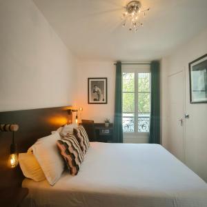 a bedroom with a bed with white sheets and a window at Hotel Le Twelve in Paris