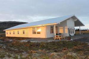 un pequeño edificio blanco y amarillo en un campo en Álftröð Guesthouse en Brautarholt
