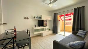 Una sala de estar con un sofá, una mesa y un televisor. en MarketHome Jardines del Mar Pool View, en Puerto de Santiago
