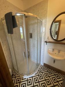 a shower in a bathroom with a sink and a mirror at Treganoon House, Lanlivery in Bodmin