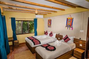 2 letti in una camera da letto con tende blu di Nepali Heritage Hotel a Kathmandu