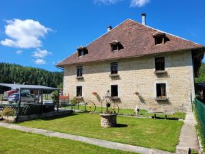 a large brick building with a grass yard at Location à la ferme entre lacs et montagnes "chez papy" in Fort-du-Plasne