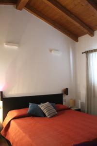 a bedroom with a large bed with an orange blanket at Casa delle rondini in SantʼAnna Arresi