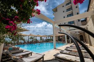 a pool at a hotel with chairs and flowers at Art Hotel in Sarandë