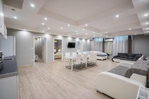 a living room with white furniture and a kitchen at Riviéra Apartmanház in Siófok