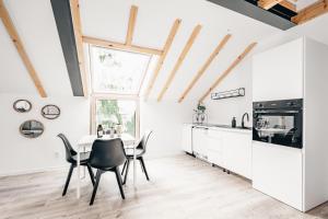 a kitchen with white cabinets and a table and chairs at Apartamenty Leszka 2, self check in 24h in Poznań