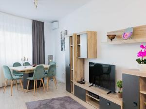 a living room with a table and chairs and a television at Regia Apartament in Oradea
