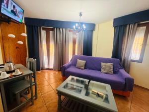 a living room with a purple couch and a table at Hotel Zacatin in Alcalá la Real