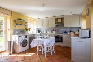 a kitchen with a table and a washing machine at Saratoga Cottage in Bruern