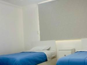 Alojamiento San Cayetano في لوخا: غرفة بيضاء بسريرين ذات أغطية زرقاء +صورة واحدة