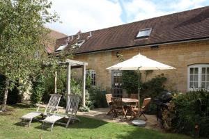 a patio with a table and chairs and an umbrella at Saratoga Cottage in Bruern