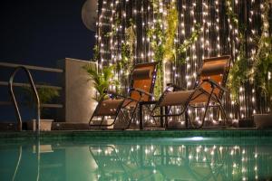 two chairs sitting next to a swimming pool at night at Gulmohar Mansion - A Boutique Stay in Jaipur