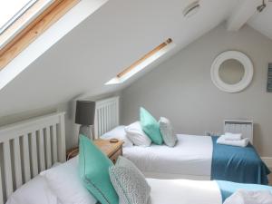 ein Schlafzimmer im Dachgeschoss mit zwei Betten und einem Fenster in der Unterkunft 5 Keeper's Cottage, Hillfield in Dartmouth