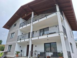 a white house with a balcony at Pensiunea Casa de pe Vale in Vulcan