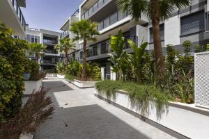 a courtyard with palm trees and a building at Essential by Charlie in Jávea