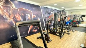 einen Fitnessraum mit Kardiogeräten und eine Wand mit einem Gemälde in der Unterkunft Flat à Beira-Mar na Praia de Cabo Branco 327 in João Pessoa