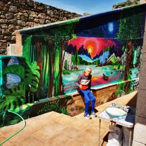 a man sitting in front of a painting on a wall at Apartamento Mar de Fora in Finisterre +4 photos