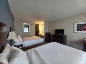 FreeportにあるBaymont by Wyndham Freeportのベッド2台とテレビがあるホテルの部屋