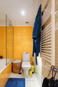 a bathroom with a toilet and a shower with yellow tiles at Thisseion Lofts George in Athens +28 photos