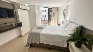 Schlafzimmer mit einem Bett, einem TV und einem Fenster in der Unterkunft Flat à Beira-Mar na Praia de Cabo Branco 327 in João Pessoa + 43 Fotos