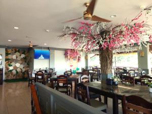 uma sala de jantar com mesas e cadeiras e uma árvore em Best Western Hotel & Casino Kamuk em Manuel Antonio