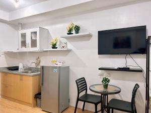 a kitchen with a table and a tv on a wall at Mesaverte Residences Cozy Studio Unit in Cagayan de Oro