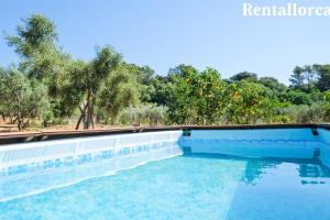 a swimming pool with blue water and trees in the background at Ses Rotes by Rentallorca in Campanet