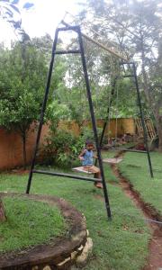 a boy sitting on a swing set in a yard at Walawe Park View Hotel in Udawalawe