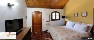 a bedroom with a bed and a flat screen tv at Pousada Bela vista Monte Verde in Monte Verde