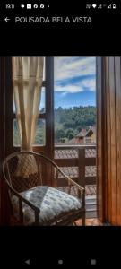 a chair sitting on a balcony looking out a window at Pousada Bela vista Monte Verde in Monte Verde