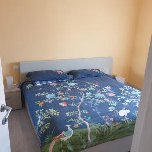 a bed with a blue comforter with birds and flowers at Appartamento al Condominio Concordia in Grado
