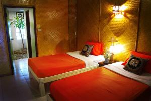 a room with two beds with red sheets and a lamp at Areeya Phuree Resort Thaton in Mae Ai