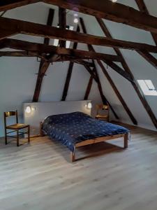 a bedroom with a bed and two chairs in a attic at Maison Village Hautefage in Hautefage