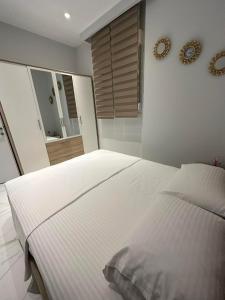 ペライアにあるLUXURY STAY by Antoniοの白いベッドと壁に時計が備わるベッドルーム1室が備わります。