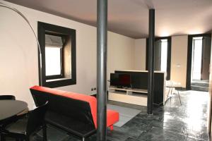un soggiorno con sedia rossa e TV di Albergo Diffuso Sauris in La Maina a Sauris