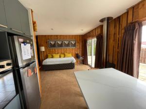 a bedroom with a bed and a kitchen with a refrigerator at Acogedora casa cerca del Bosque El Canelo in Algarrobo