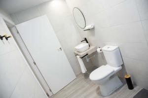 ein weißes Bad mit einem WC und einem Spiegel in der Unterkunft Pregonero Urban Suites - Naranja in Soria + 18 Fotos