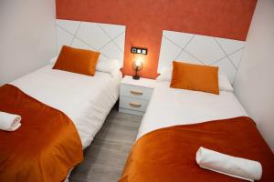 2 Betten in einem Zimmer mit orangefarbenen Wänden in der Unterkunft Pregonero Urban Suites - Naranja in Soria