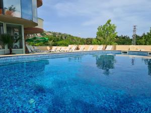 a large swimming pool with chairs and a building at HOTEL PARIS Relax Zone in Balchik