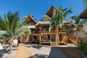 a house on the beach with palm trees at Mangle Rojo Palafitos in La Manzanilla