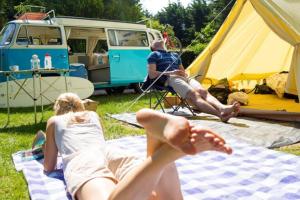 two women laying on a blanket in front of a tent at Headgate Farm Camp Site - Pitches Only - Bring your own tent or van in South Molton