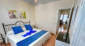 a bedroom with a large bed with blue pillows at El sombrerito 5 in Caleta de Sebo