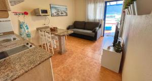 a kitchen and a living room with a couch at El sombrerito 5 in Caleta de Sebo