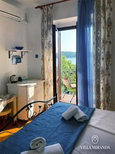 a bedroom with a bed with a blue blanket and a window at Apartments Vila Miranda on the beach in Barbat na Rabu