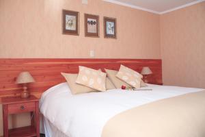 a bed with two pillows and two nightstands at Hotel Borde Lago in Puerto Varas