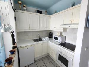 a kitchen with white cabinets and a sink and a microwave at Rocas del Mar 408 in Costa Del Silencio +9 photos