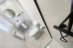 ein Badezimmer mit einer weißen Toilette und einem Spiegel in der Unterkunft Pregonero Urban Suites - Azul in Soria + 20 Fotos