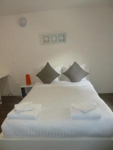 1 cama blanca grande con 2 almohadas en Résidence Hôtelière Louise, en Estrasburgo