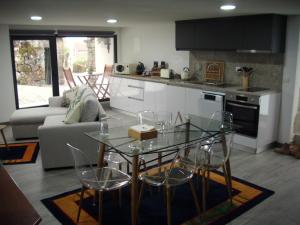 a kitchen and living room with a glass table and chairs at Casa do avô Serafim in Cetos