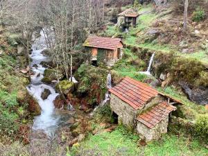 a small house on a hill next to a river at Casa do avô Serafim in Cetos